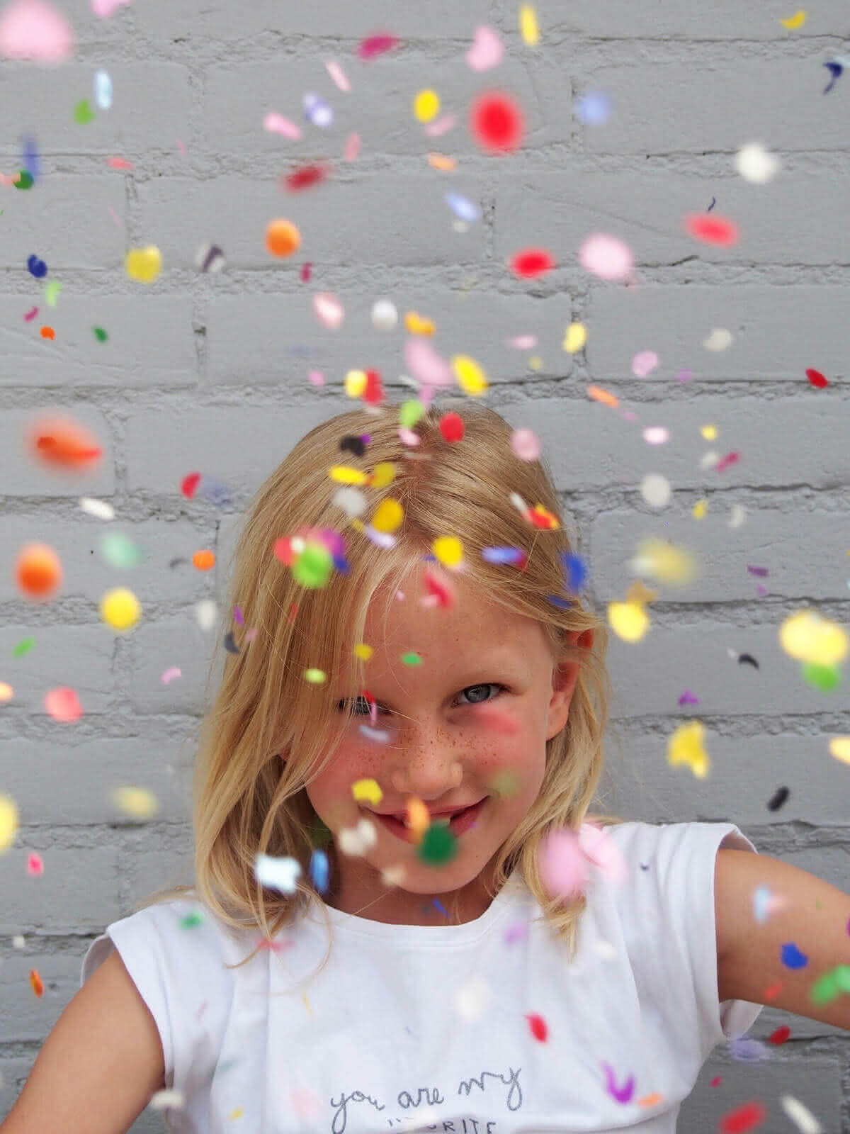 Mädchen im weissen Kleid mit Konfetti