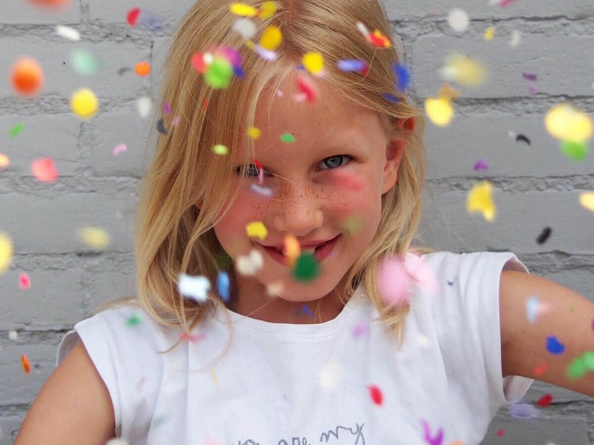 Mädchen im weissen Kleid mit Konfetti